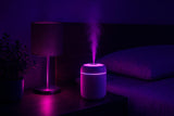 Mini humidificador en la mesita de noche con ambiente morado relajante